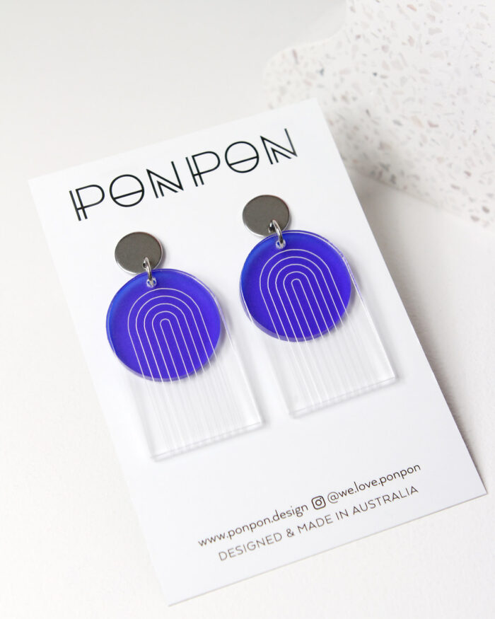 Pon Pon Through the Arch earrings in clear etched and frosted dark blue acrylic