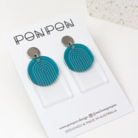 Pon Pon Through the Arch earrings in clear etched and frosted teal acrylic